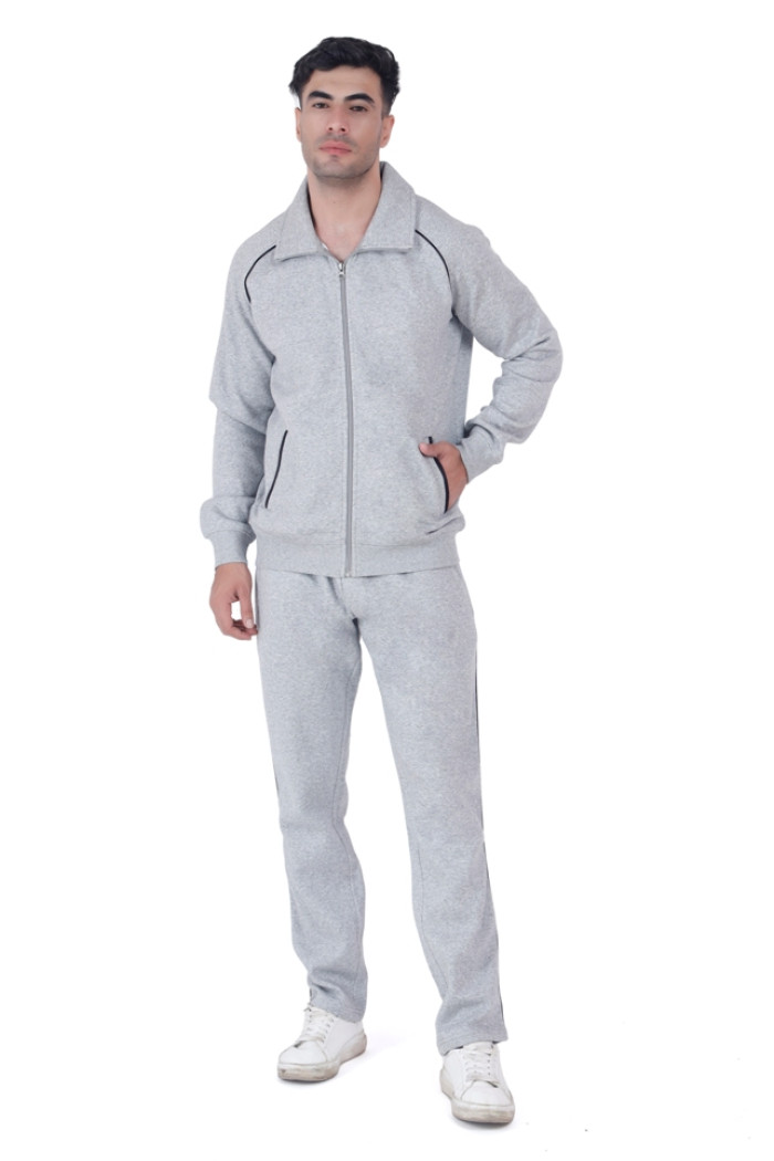 A man wearing Trufit’s Grey Grindle tracksuit with black piping and a front zipper, standing in a relaxed pose with one hand in his pocket, paired with white sneakers against a plain white background.